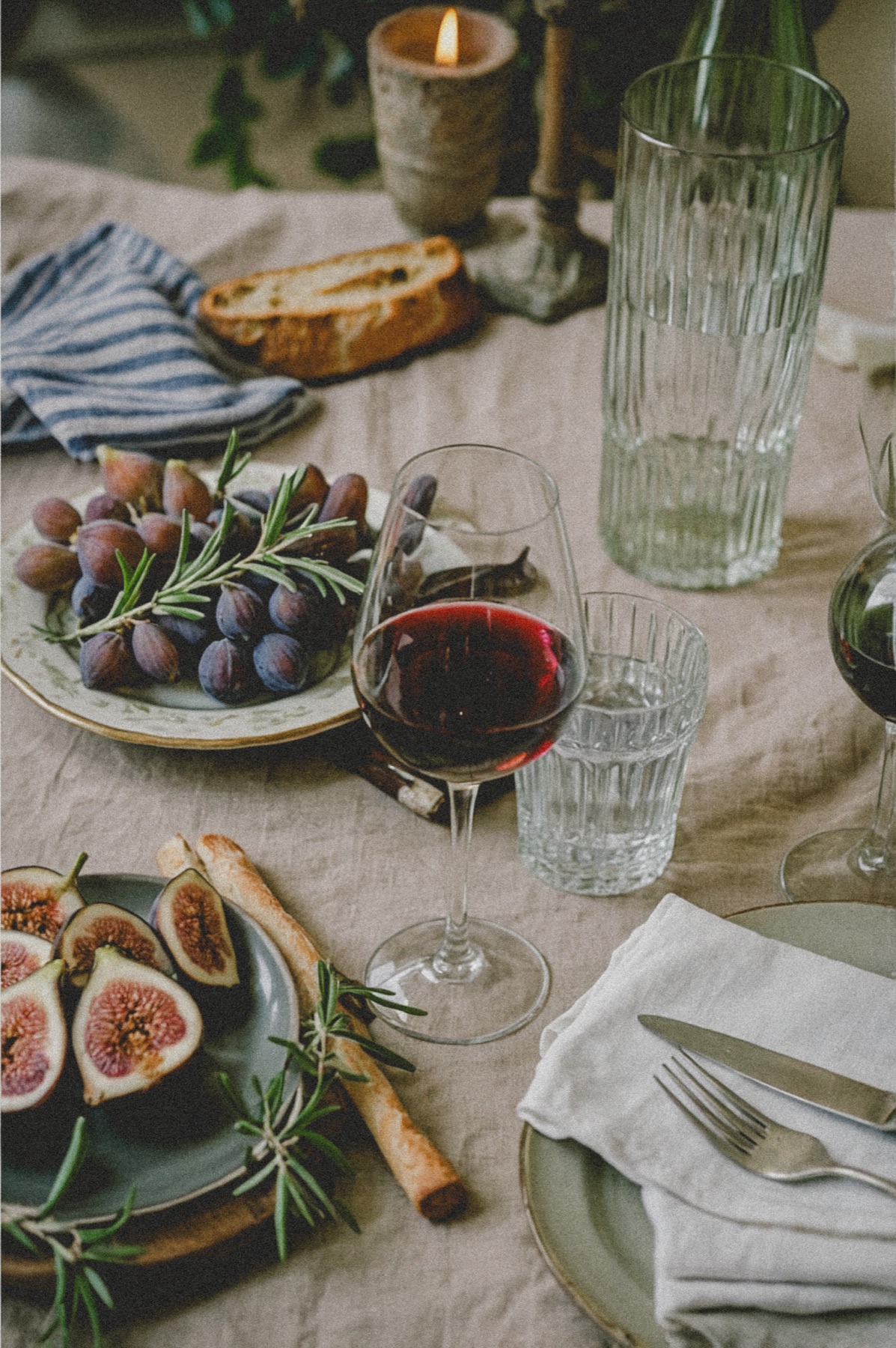 Figs, wine and bread arranged on a sunlit table
