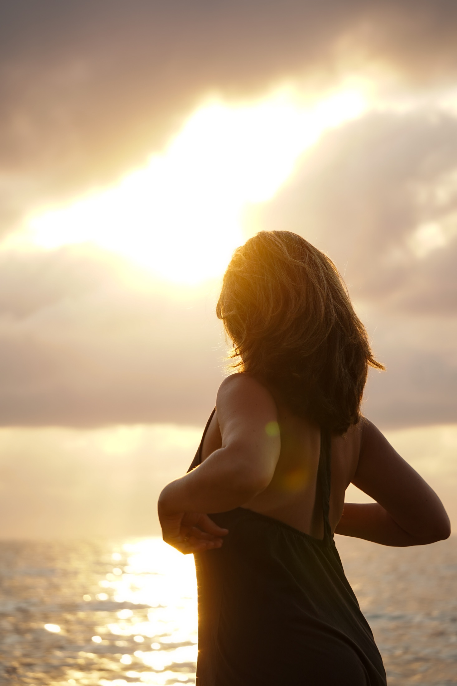 Niki standing in golden sunset light beside the ocean