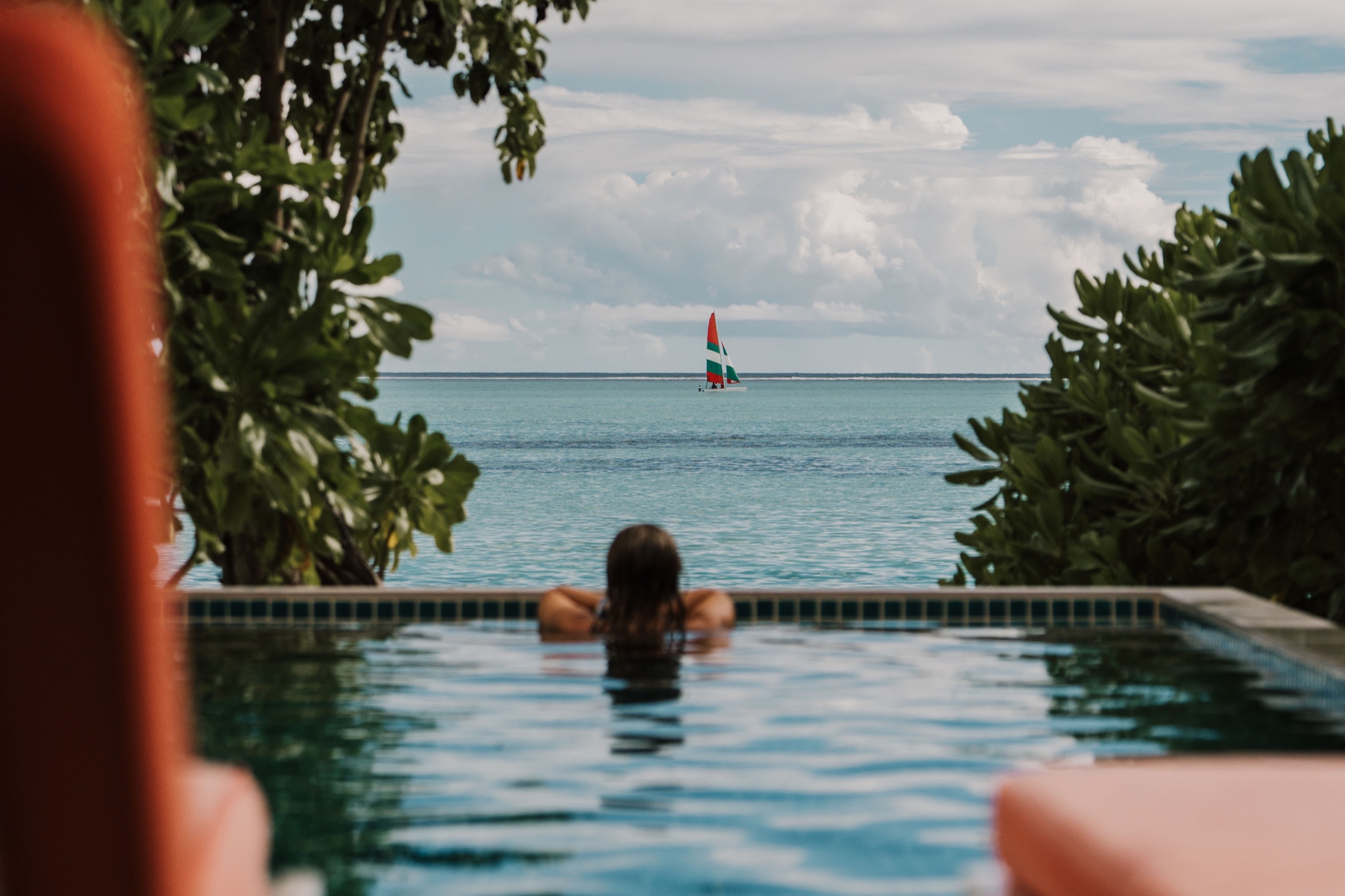 A woman looking out over a tropical pool and turquoise ocean